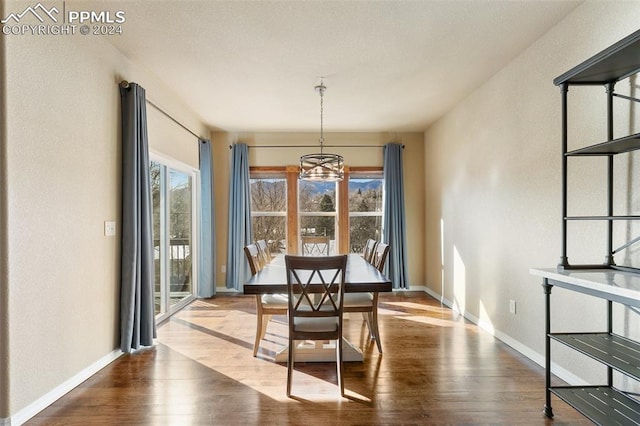 dining space with wood-type flooring, an inviting chandelier, and a wealth of natural light