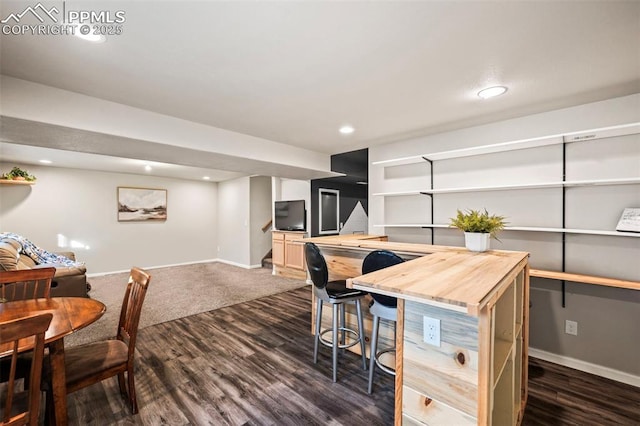 interior space featuring dark colored carpet, a center island, a kitchen bar, and wooden counters