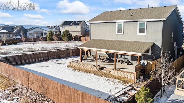 snow covered rear of property with a patio area