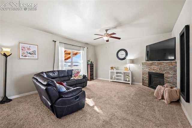 carpeted living room with a stone fireplace and ceiling fan