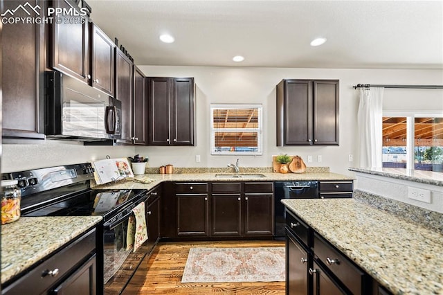 kitchen featuring dark brown cabinetry, sink, black appliances, and light hardwood / wood-style flooring