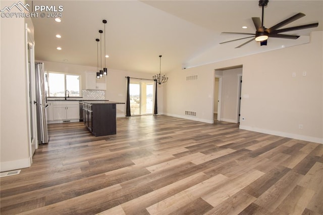 unfurnished living room featuring ceiling fan with notable chandelier, hardwood / wood-style flooring, lofted ceiling, and sink