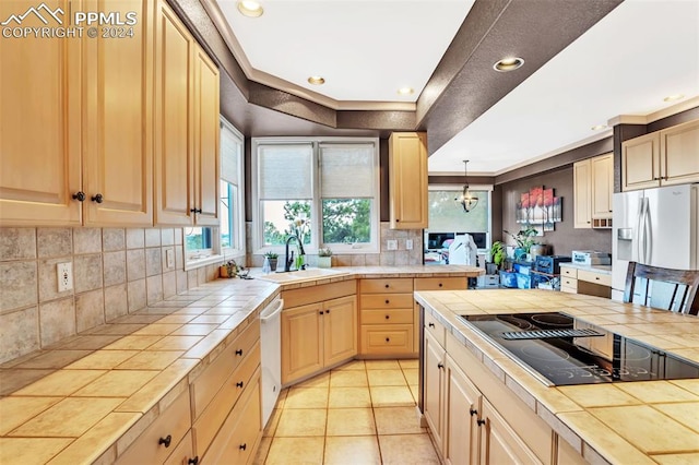 kitchen featuring tile countertops, sink, hanging light fixtures, and appliances with stainless steel finishes