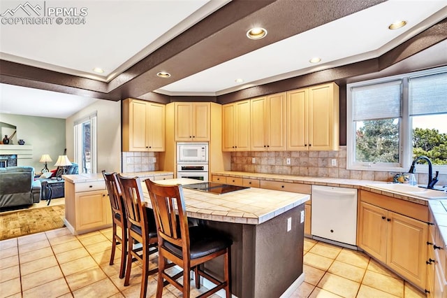 kitchen with tile countertops, white appliances, a center island, and sink