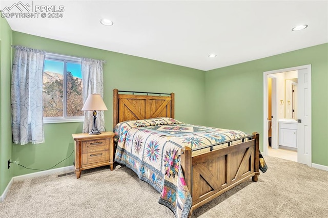 bedroom featuring ensuite bathroom and light colored carpet