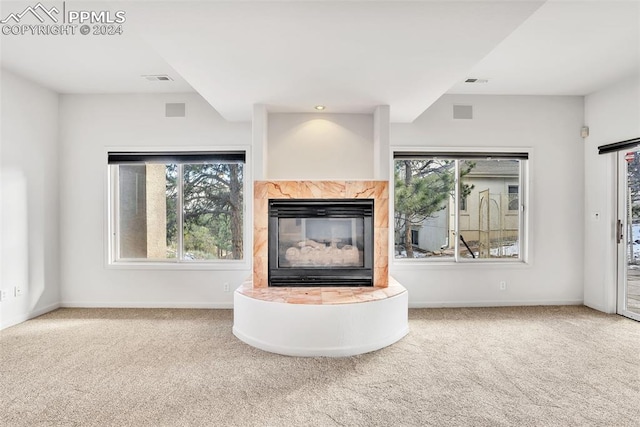 unfurnished living room featuring a fireplace, carpet floors, and a wealth of natural light