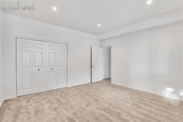 unfurnished bedroom featuring light carpet and a closet