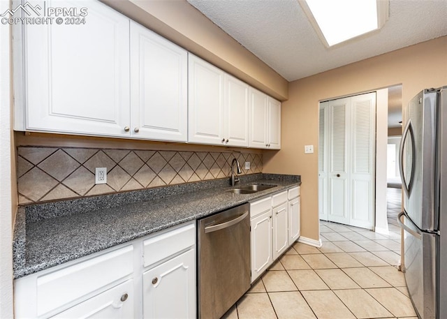 kitchen with white cabinets, sink, light tile patterned floors, appliances with stainless steel finishes, and tasteful backsplash