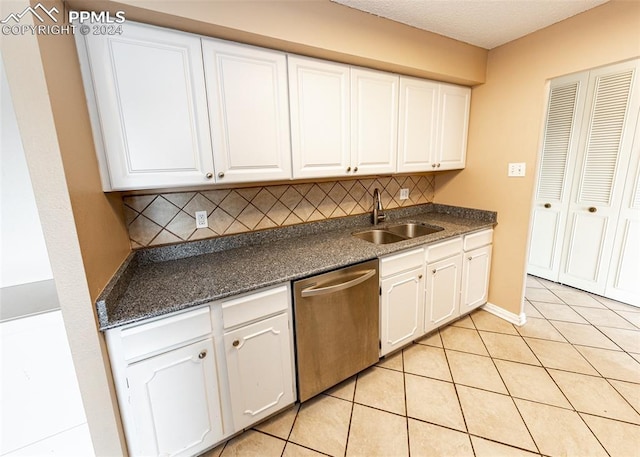 kitchen with backsplash, sink, light tile patterned floors, dishwasher, and white cabinetry