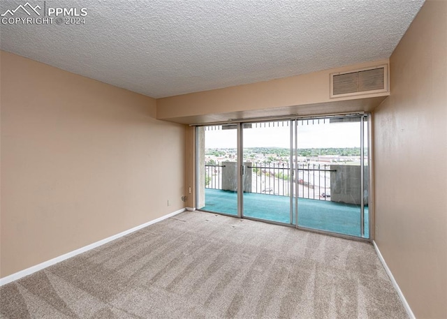 empty room featuring a textured ceiling, light colored carpet, a wealth of natural light, and a water view