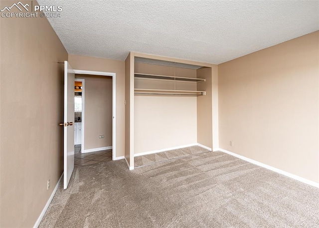 unfurnished bedroom with a textured ceiling, carpet floors, and a closet