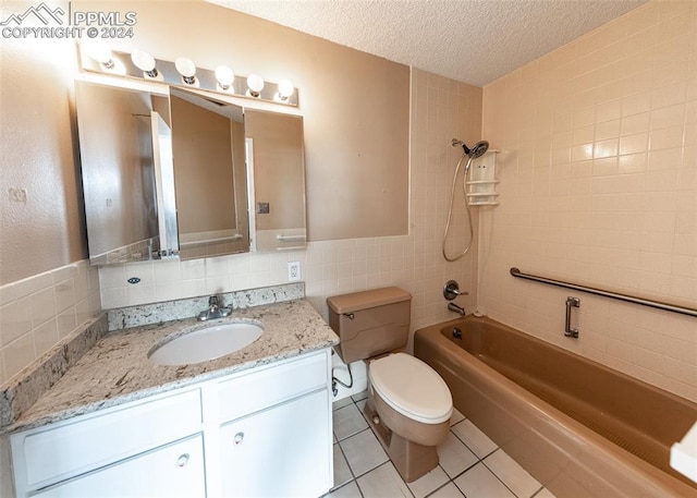 full bathroom with tiled shower / bath combo, a textured ceiling, toilet, vanity, and tile walls