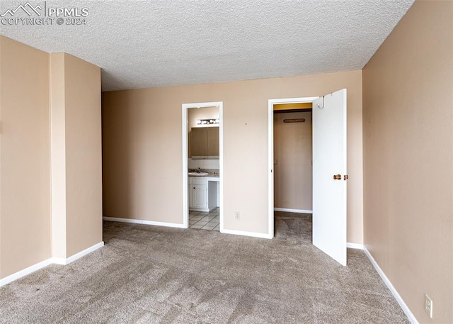 unfurnished bedroom with light colored carpet, a walk in closet, and ensuite bath