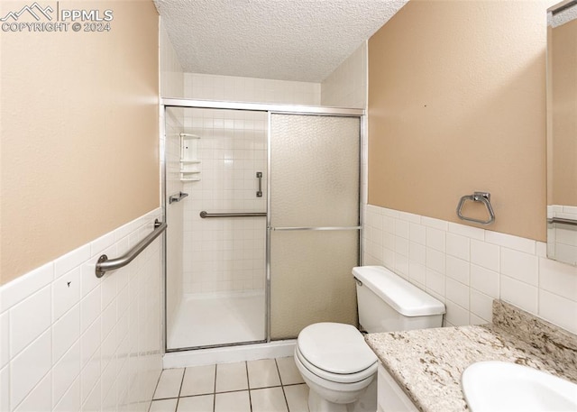 bathroom featuring walk in shower, tile patterned flooring, a textured ceiling, toilet, and tile walls