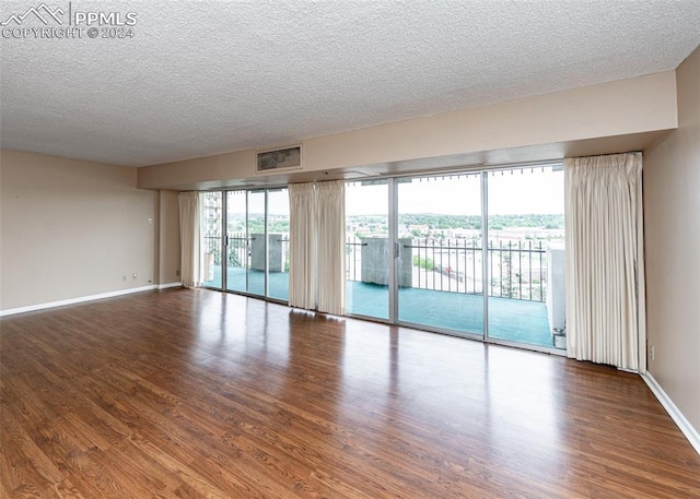 spare room featuring hardwood / wood-style floors and a textured ceiling