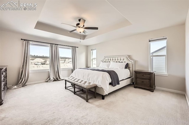 carpeted bedroom with a tray ceiling and ceiling fan