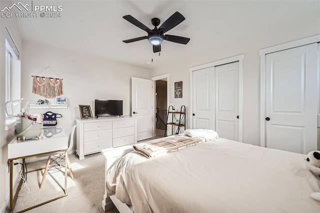 carpeted bedroom featuring ceiling fan and two closets