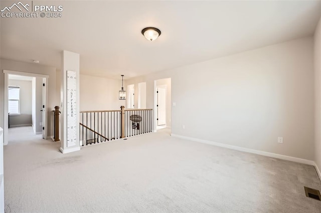 unfurnished room featuring light carpet and an inviting chandelier