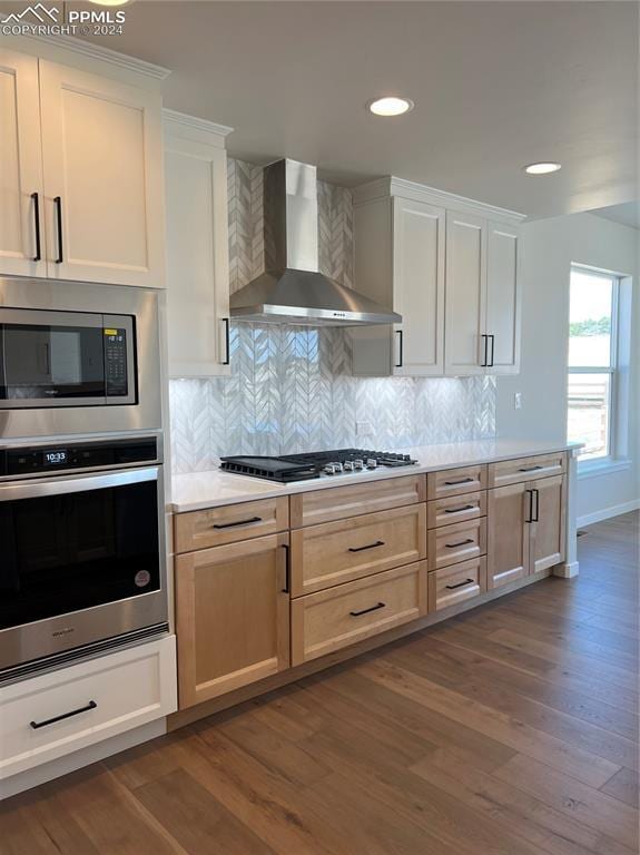 kitchen featuring backsplash, white cabinets, wall chimney range hood, dark hardwood / wood-style flooring, and stainless steel appliances