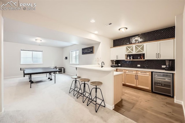 kitchen featuring a kitchen breakfast bar, wine cooler, plenty of natural light, and light hardwood / wood-style flooring