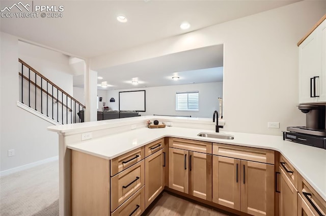 kitchen with light brown cabinets, kitchen peninsula, sink, and carpet floors