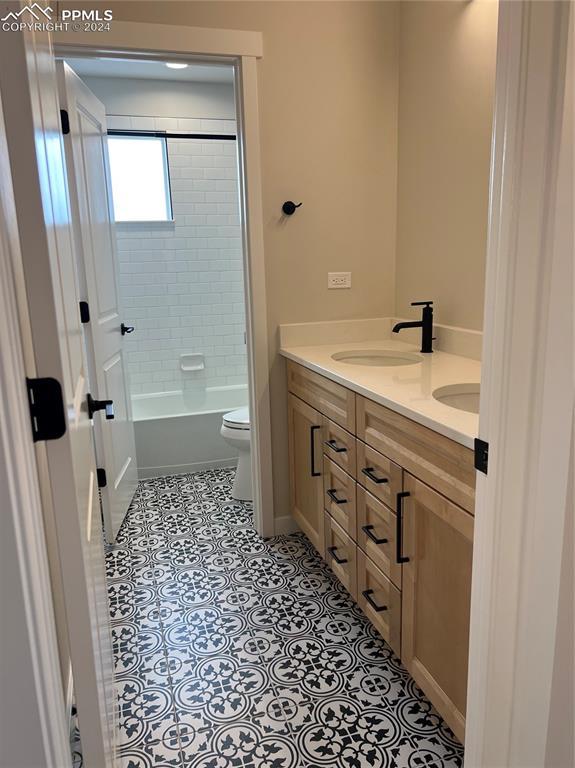 full bathroom with tiled shower / bath, tile patterned flooring, vanity, and toilet