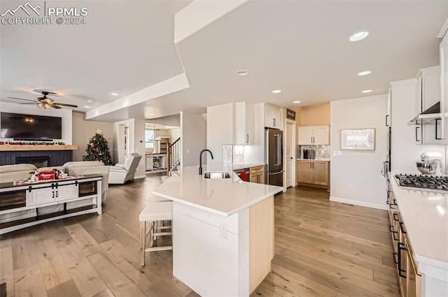 kitchen with a kitchen breakfast bar, light wood-type flooring, stainless steel appliances, and white cabinetry