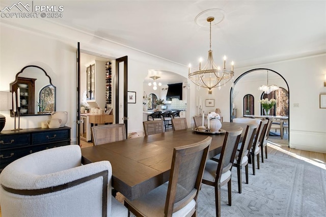 dining area featuring wood-type flooring, crown molding, and an inviting chandelier