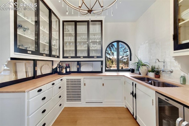 bar featuring white cabinetry, sink, tasteful backsplash, wine cooler, and light hardwood / wood-style flooring