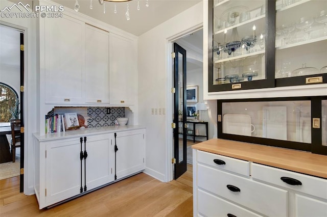 bar featuring decorative backsplash, light hardwood / wood-style flooring, and white cabinets