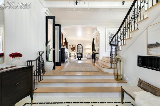 staircase with hardwood / wood-style flooring and ornamental molding