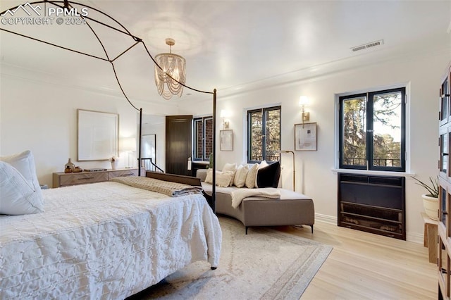 bedroom featuring ornamental molding, a notable chandelier, and light wood-type flooring