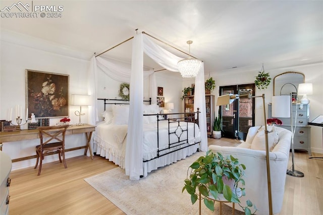 bedroom featuring ornamental molding, wood-type flooring, and an inviting chandelier