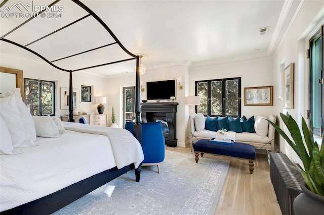 bedroom with light hardwood / wood-style floors, crown molding, and multiple windows