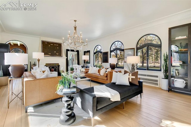 living room featuring an inviting chandelier, crown molding, and light hardwood / wood-style flooring