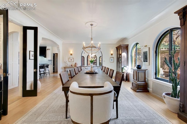 dining space with light hardwood / wood-style floors, crown molding, and a chandelier