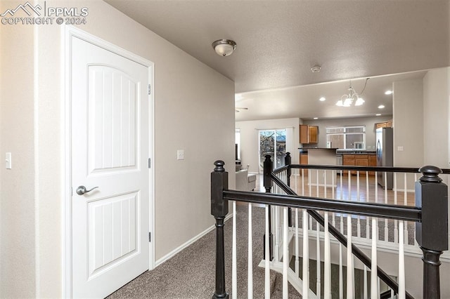 hall featuring carpet flooring and a notable chandelier