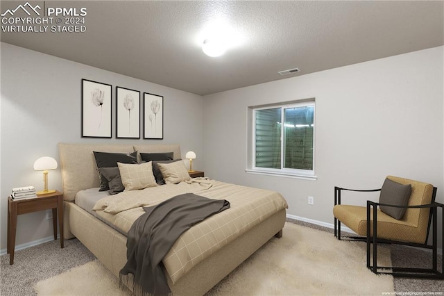 bedroom with light carpet and a textured ceiling