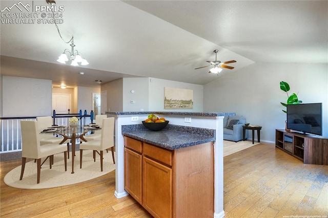 kitchen with ceiling fan with notable chandelier, vaulted ceiling, pendant lighting, light hardwood / wood-style flooring, and a center island