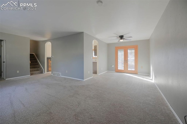 unfurnished living room featuring ceiling fan, light colored carpet, and french doors