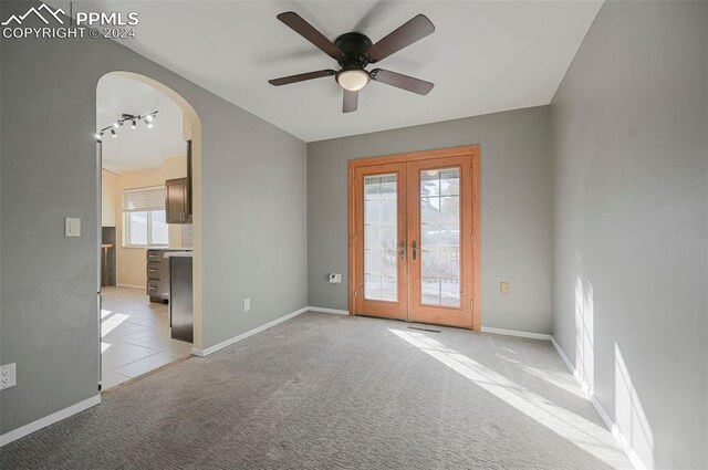 spare room with ceiling fan, light carpet, and french doors