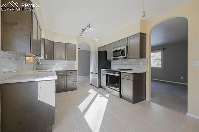 kitchen with dark brown cabinets, light tile patterned floors, stainless steel appliances, and sink