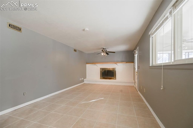 unfurnished living room with a fireplace, light tile patterned floors, and ceiling fan