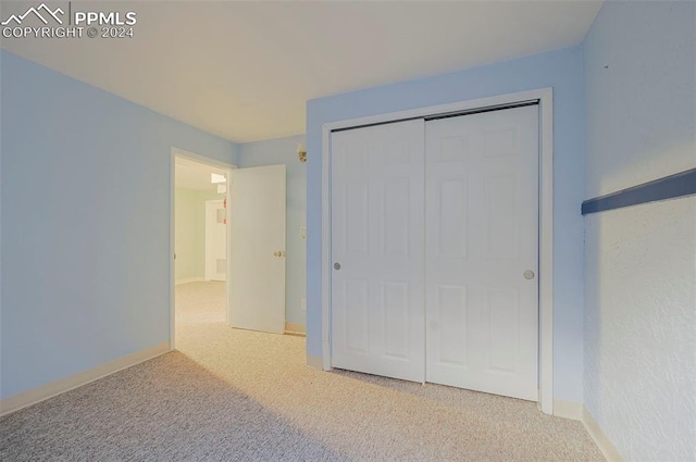 unfurnished bedroom featuring light colored carpet and a closet