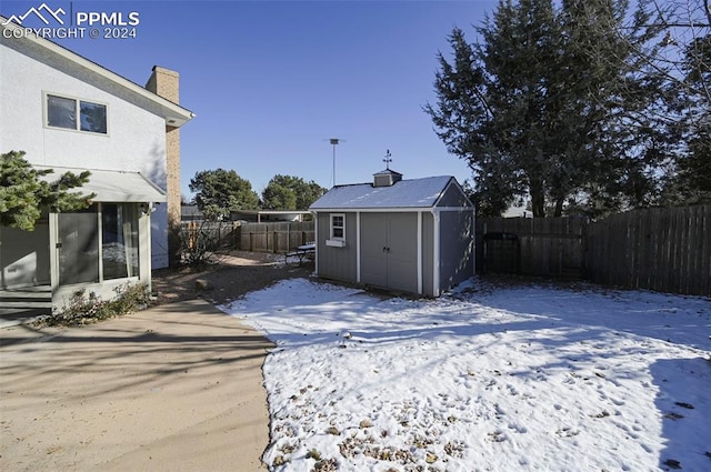 snowy yard featuring a storage shed