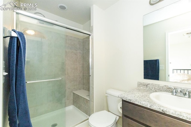 bathroom featuring vanity, toilet, and a shower with door