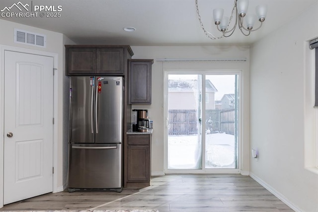 kitchen featuring dark brown cabinets, light hardwood / wood-style floors, stainless steel refrigerator, and a chandelier