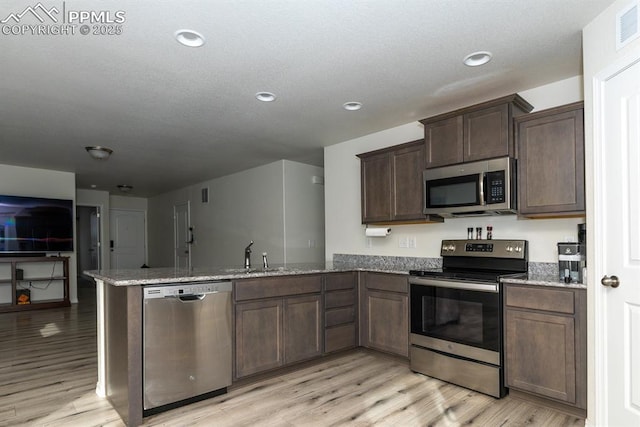 kitchen featuring kitchen peninsula, sink, light hardwood / wood-style flooring, and appliances with stainless steel finishes