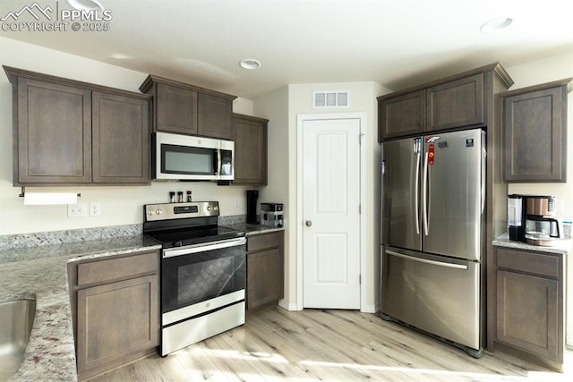 kitchen featuring light stone countertops, dark brown cabinets, stainless steel appliances, and light hardwood / wood-style flooring