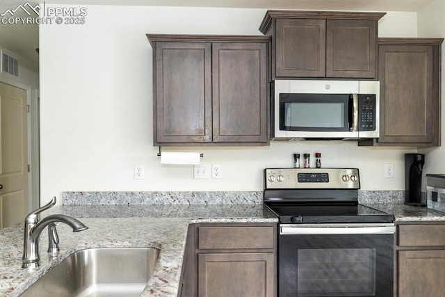 kitchen featuring dark brown cabinets, sink, light stone countertops, and stainless steel appliances